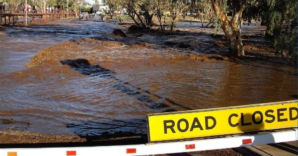 A road closed sign at the flooded Todd River in Alice Springs